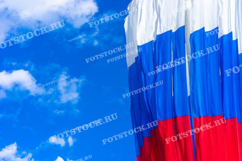 На фотографии изображён флаг Российской Федерации на фоне ясного голубого неба с белыми облаками. 
Это изображение может быть использовано для праздничных мероприятий, образовательных материалов, новостей или как элемент дизайна в публикациях, посвящённых России.